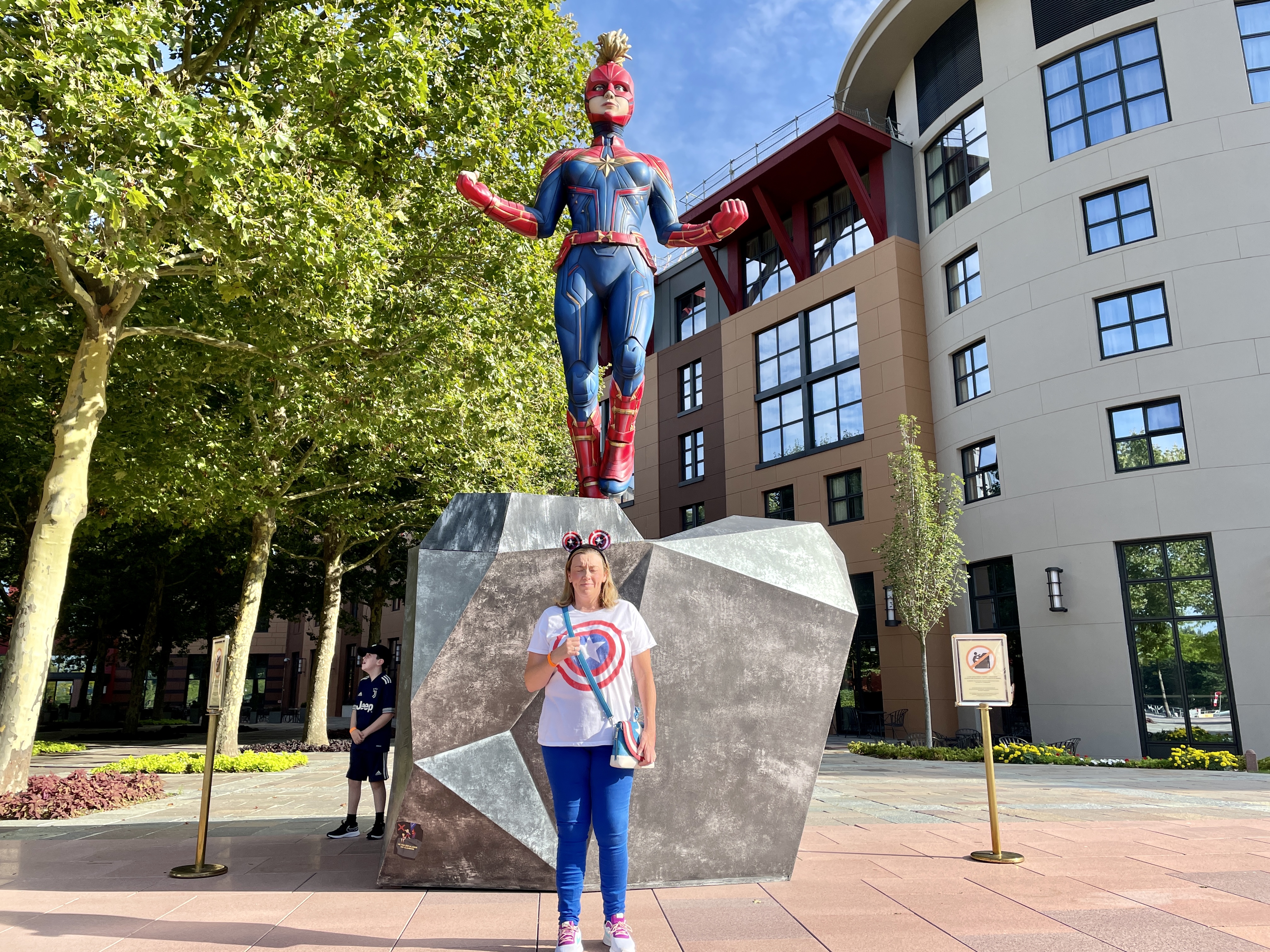 woman standing under a captain marvel statue