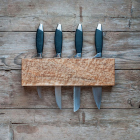 birdseye maple wall-mounted knife rack with four knives inserted into the slot along the top