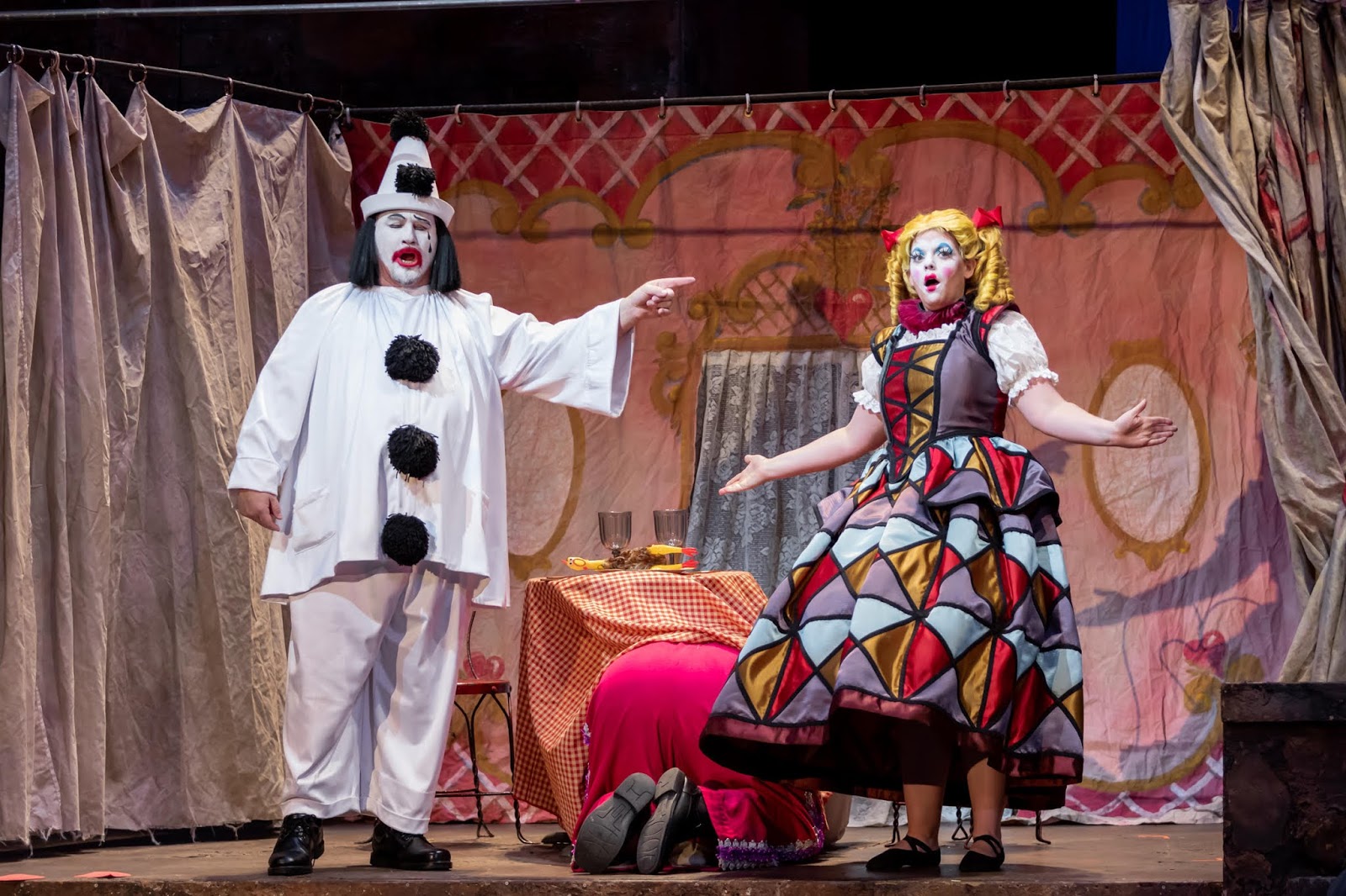 IN REVIEW: (from left to right) tenor CARL TANNER as Canio, baritone KIDON CHOI as Tonio (hiding under table), and soprano MELINDA WHITTINGTON as Nedda in North Carolina Opera's January 2020 production of Ruggero Leoncavallo's PAGLIACCI [Photograph by Eric Waters, © by North Carolina Opera]