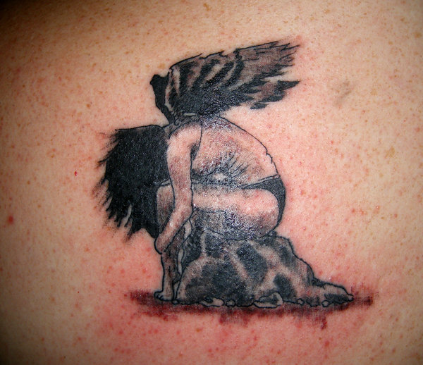 Fallen angel on rock tattoo.