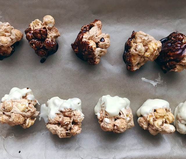 Two rows of popcorn balls, one dipped in white chocolate and another in milk chocolate