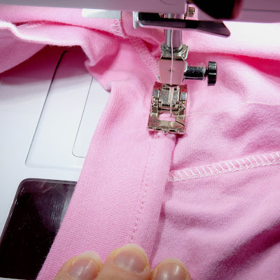 The neckline binding is wrapped round the seam allowance and is being sewn down with Bernina manual buttonhole foot #3.