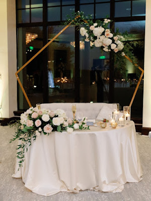sweetheart table with golden pentagon arch and floral