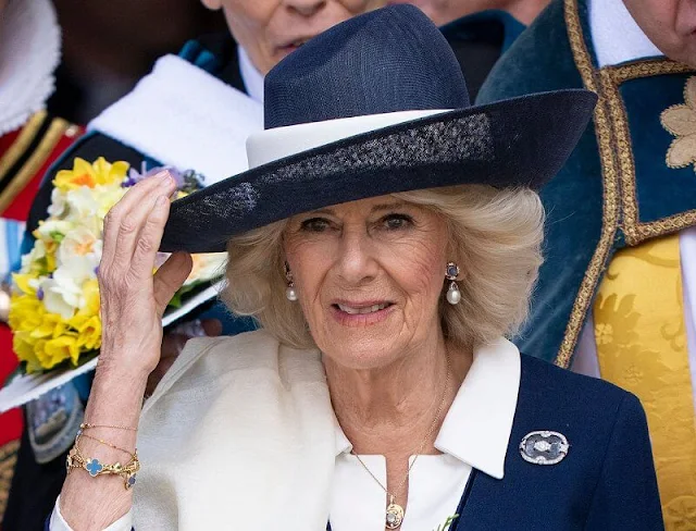 Queen Camilla wore a navy and white dress by Fiona Clare and a Philip Treacy hat. Queen Mother's Rock Crystal brooch