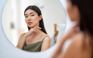 A woman looking at her positive self-reflection in the mirror.