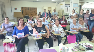 Foto de grupo, las alumnas que han recibido sus costurero sentadas en el aula y al fondo los organizadores y la profesora.