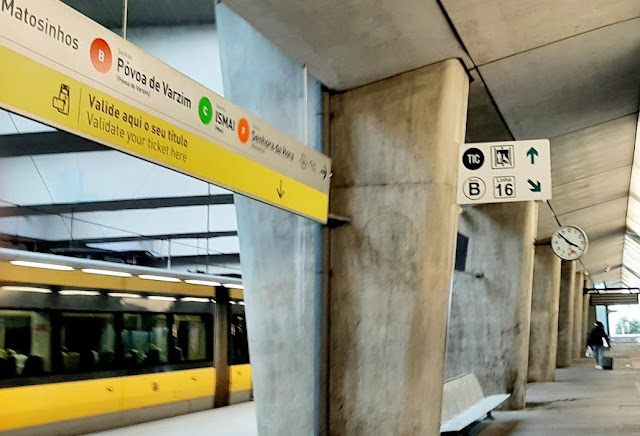 metro parado na estação, pessoa com mala parada e vários painéis de sinalização