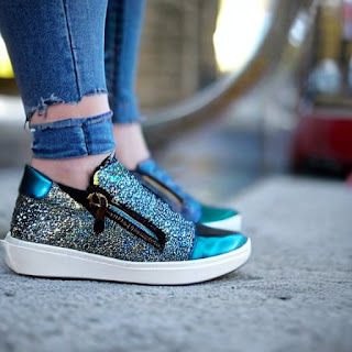 Woman wearing fashionable blue lady's disco-style zip-up sneakers without a heel. There are no shoelaces.