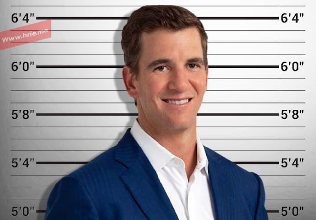 Eli Manning posing in front of a height chart background
