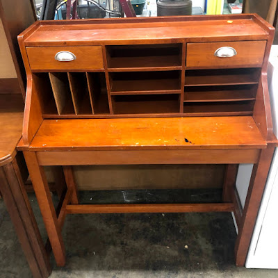 A secretary desk with orangey brown chipped finish and silver handles