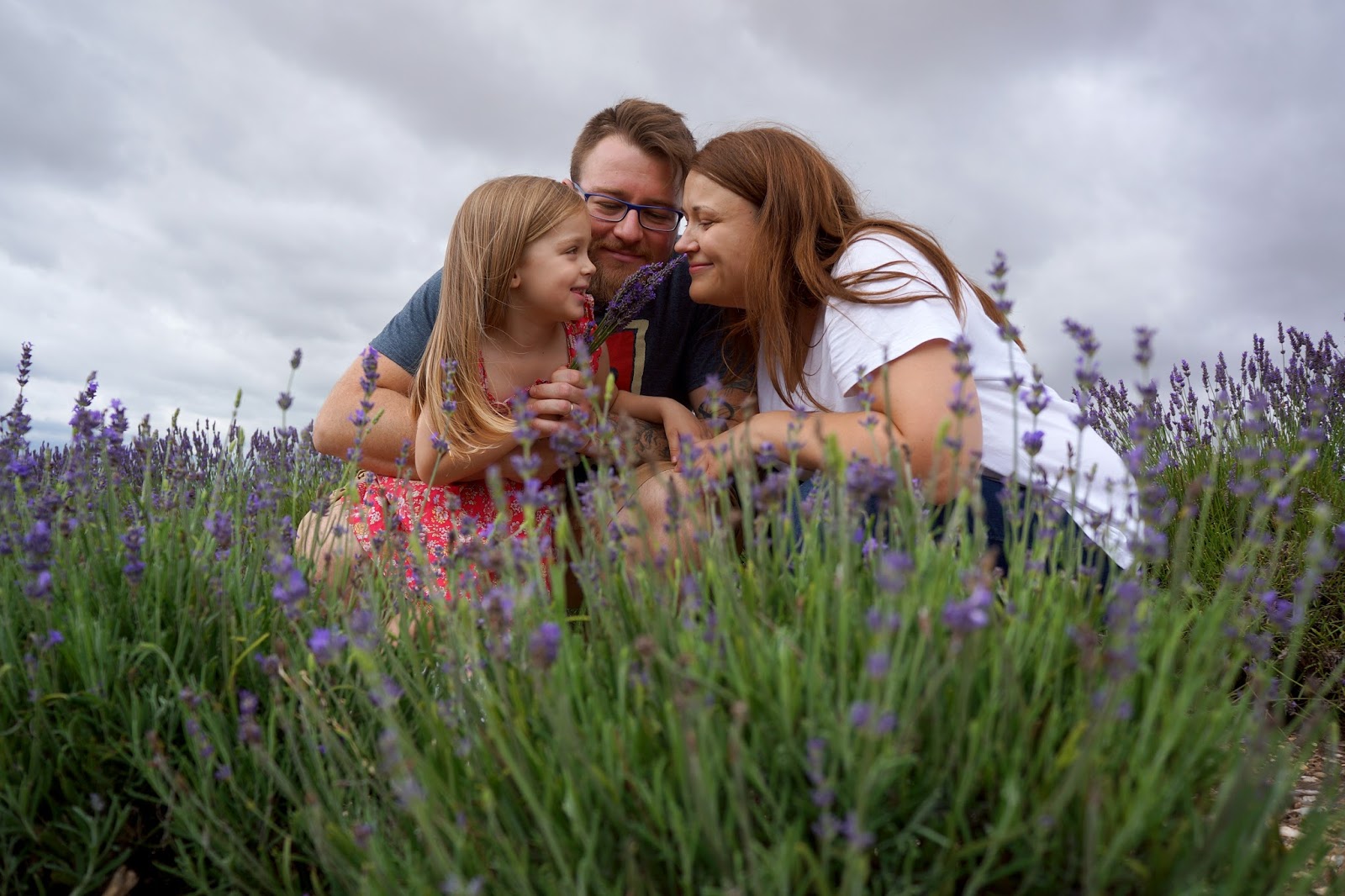 mum dad and daughter smiling family portrait at lavender fields