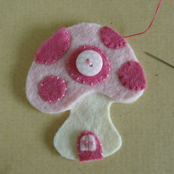 Hand stitching pink spots onto the felt design toadstool