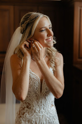bride smiling in beaded wedding gown putting in earrings
