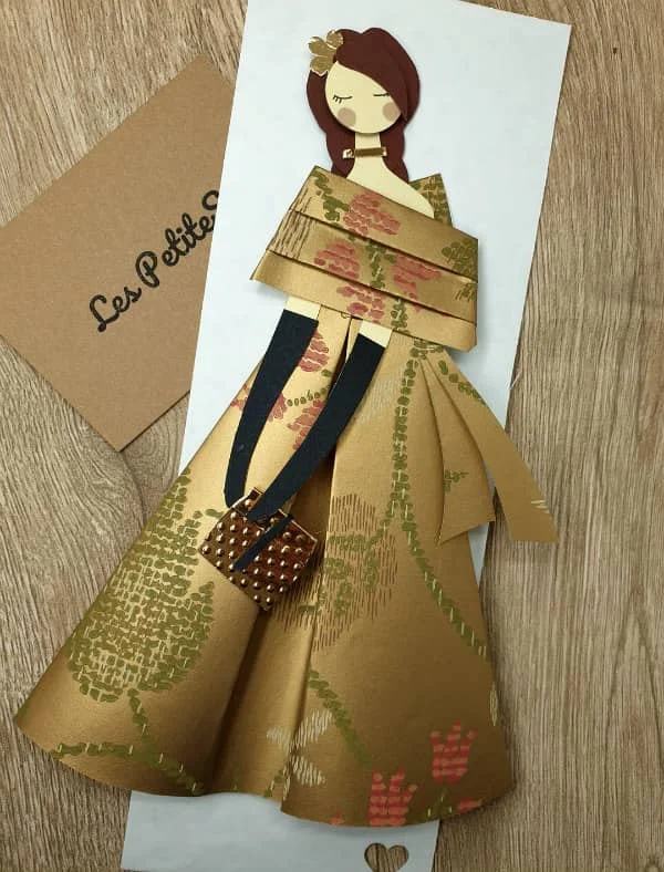 glamorous female figure made of decorative papers placed alongside Les Petites business card