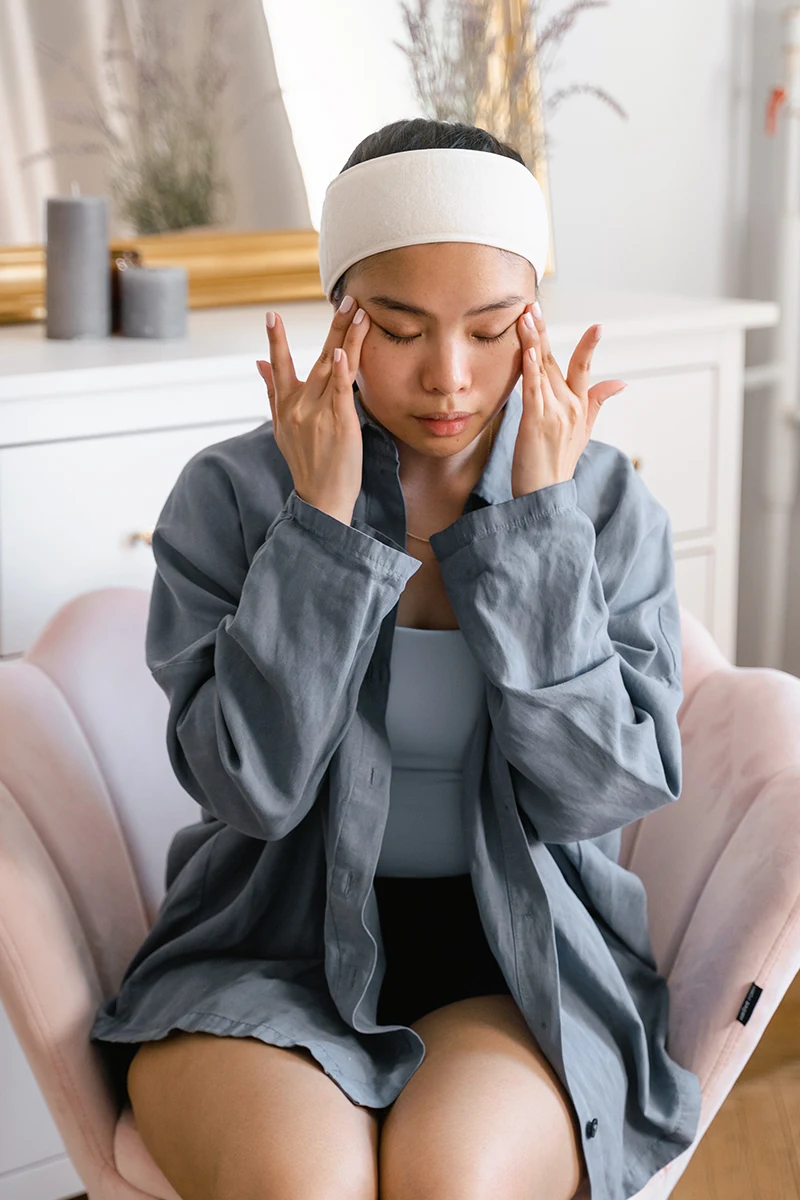 woman is sitting on a chair and massages her face