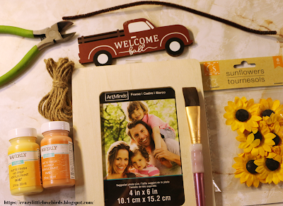 Craft materials such as paint, twine, paper flowers and picture frame on a table