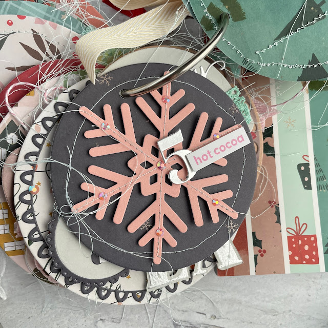 Christmas Advent Calendar Mini Album created with the Scrapbook.com Christmas patterned paper pad, nested decorative circles die, nested tree die, little envelopes die, snowflake die, nested pockets die, nested tags die and more.