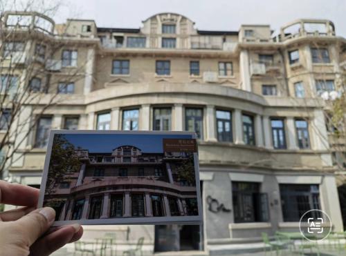 Hand met ansichtkaart van gebouw met daarachter het gebouw zelf: 黑石公寓