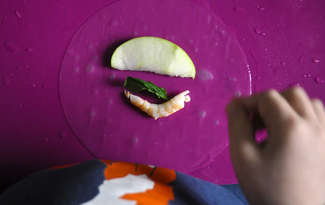 La oblea trasparente, con un trozo de manzana, una hoja de hierbabuena y una gamba