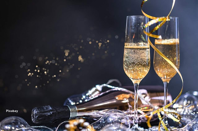 Mesa de fim de ano com garrafa de champanhe e copos.