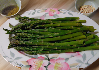 Plate of asparagus with dressing and almonds on side