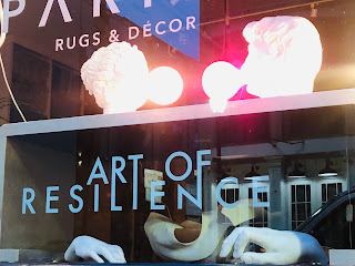 The view in a store window:  Two statue heads blowing pink bubbles of gum, with the caption, "Art of Resilience."