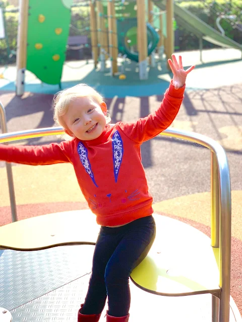 A toddler on a roundabout in the playground