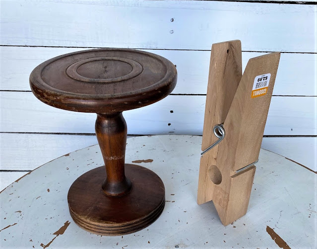 Photo of a pedestal candleholder and a large wooden clothespin.