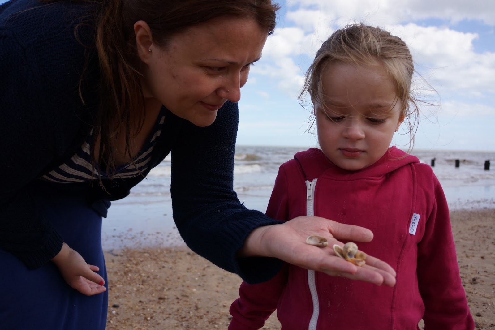 mum showing seashells to daughter