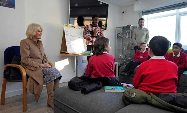 Queen Camilla wore a beige midi coat and floral print dress. Beige suede boots. The Norbrook Community Centre in Wythenshawe