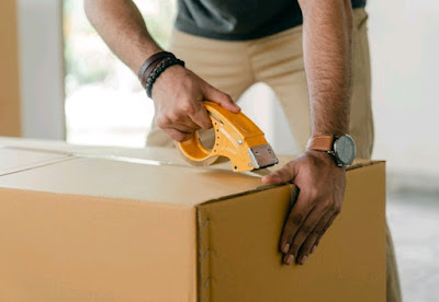 A man taping a cardboard box shut.