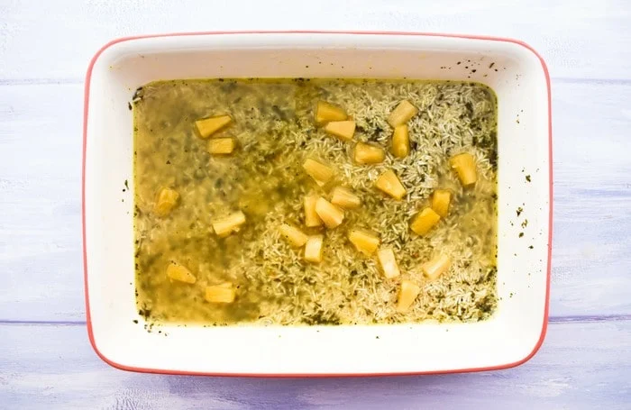 rice and pineapple in stock in a rectangular baking dish