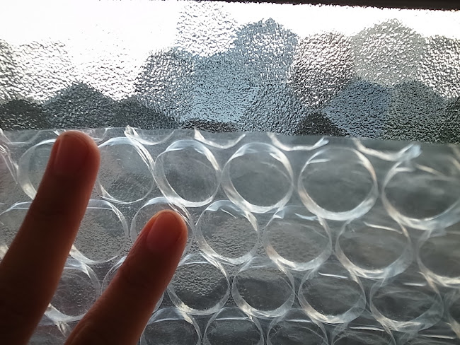 窓の凹凸ガラスに断熱シートを貼っている