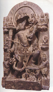 Vishnu as Varaha, the boar avatar, ascending from the ocean depths. In the crook of one of his left arms he bears the rescued goddess Bhumi or Prithivi, the earth. From above Brahma (right) and Shiva (left) look on, while human worshippers pay homage. Chauham style slate carving, twelfth century. Victoria and Albert Museum, London. 