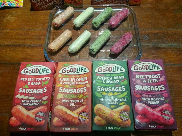 Goodlife vegetarian sausages displayed on a table, loose sausage and boxes to show varieties