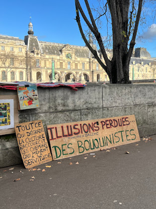 "Verlorene Illusionen", Schilder am Ufer, auf dem anderen steht das in der Fotounterschrift übertragene Zitat: Tout ce qui dégrade la culture raccourcit les chemins qui mènent à la servitude (Camus).