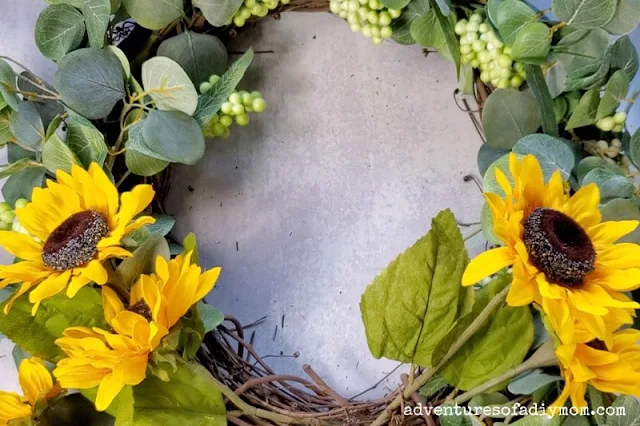 Adding sunflowers to the wreath frame in a bouquet bundle at the base of the wreath.