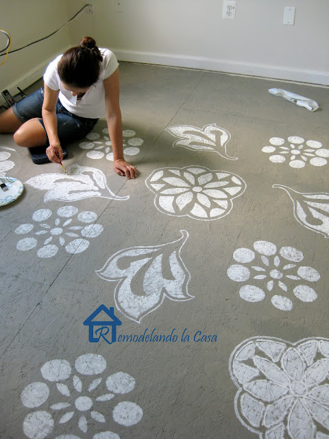 woman painting floral designs on floor, gray, white, brush, paint