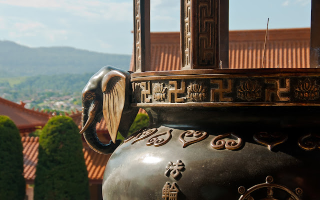 Close-up of a metal incense burner with an elephant, swastikas, and other decorations. At Nan Tien Temple.