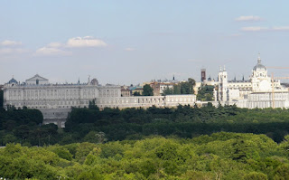 Vista del palacio y la catedral de la Almudena desde una colina de la Casa de Campo. Por medio, las copas de los árboles del parque.