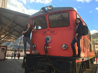 Kaitlin and Jossel standing on a red train car in Alausí, Ecuador