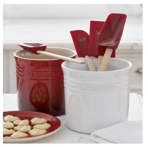 white and red stoneware utensil holders; white one holds spatulas