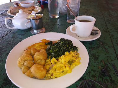 A Jamaican Breakfast of Ackee and Saltfish, Callaloo and Saltfish, Fried Plantains, and Fried Dumplings with a cup of mint tea