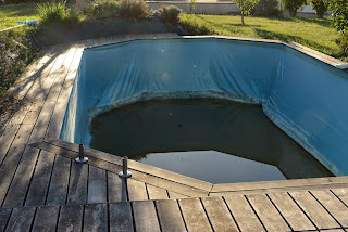 Piscine en bois vidée, liner enfoncé par les cailloux