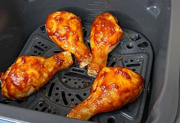 BBQ chicken drumsticks cooking in an air fryer.