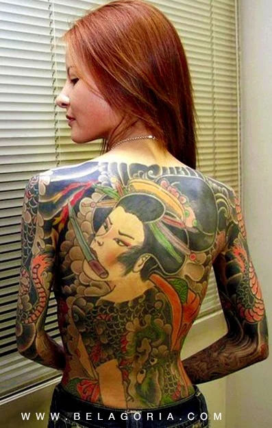 Vemos a una mujer peliroja posando de espaldas, tiene un tatuaje de geisha