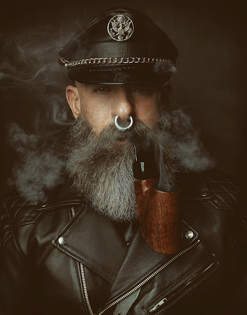 Bearded Leatherman in full gear smoking pipe