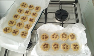 Em cima do fogão, biscoitos na forma forrada com papel manteiga