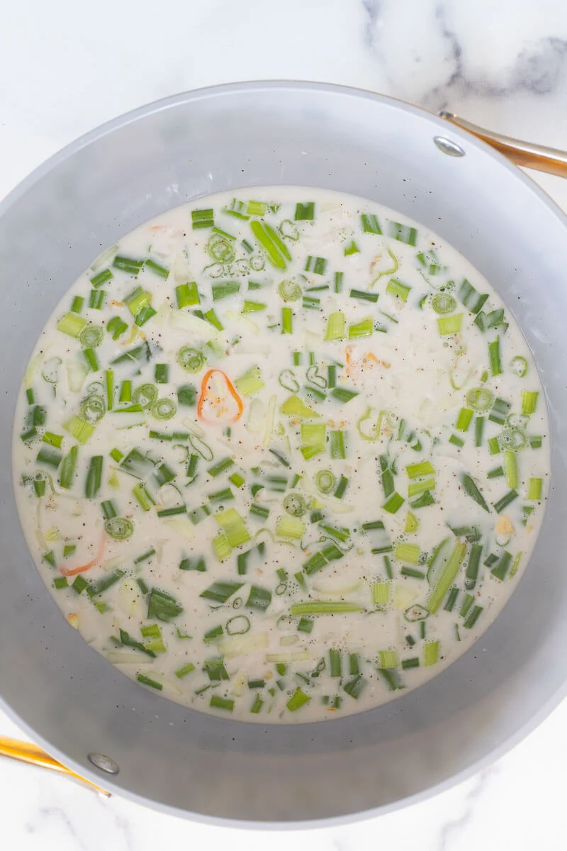 Coconut milk with scallion and peppers about to be boiled.