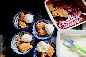 preparing to serve fresh cherry and blueberry cobbler with vanilla ice cream